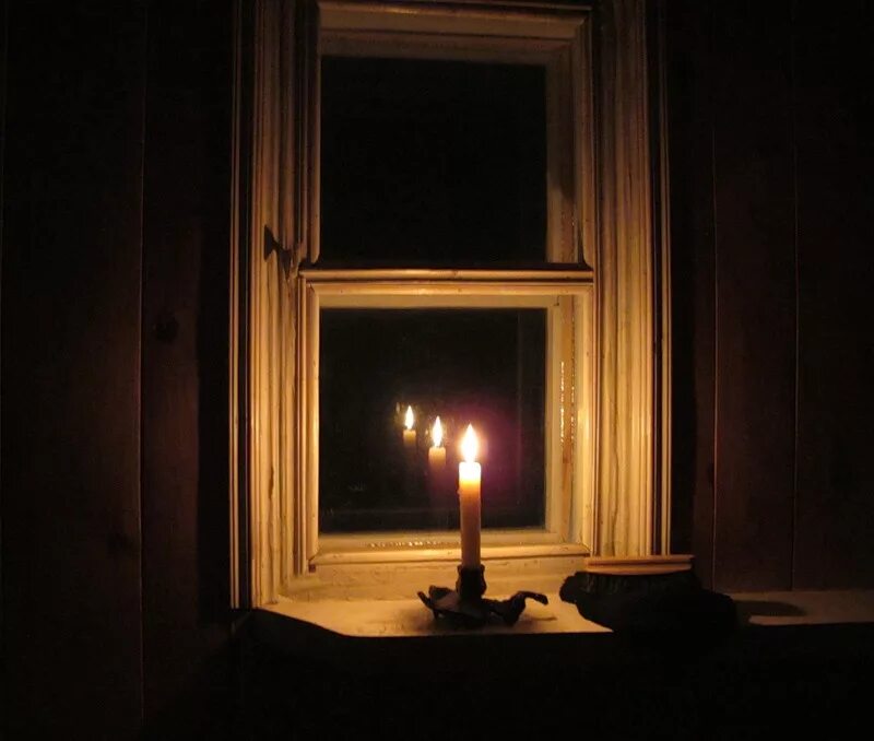 На столе стоит свеча которая отражается. Темная комната со свечами. Свеча в окне. Комната со свечами. Горящие свечи в комнате.