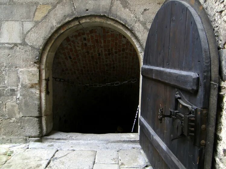 Открывает потайную дверь. Дверь в подвал. Дверь в подвале замка. Двери замка средневековья. Подвал старого замка.
