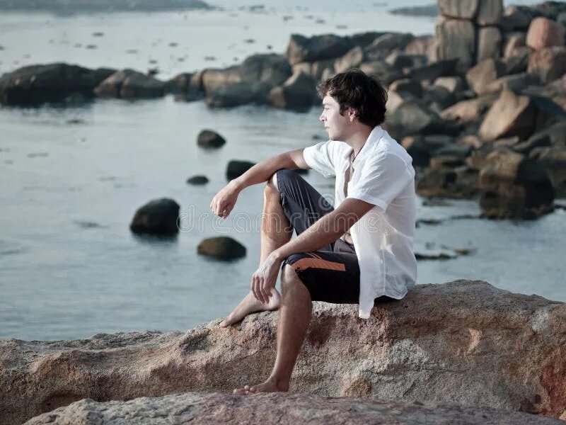 Есть я у мужа у камня. Мужчина сидит на Камне. Парень на Камне. Парень сидит на берегу моря. Мужская фотосессия на камнях.