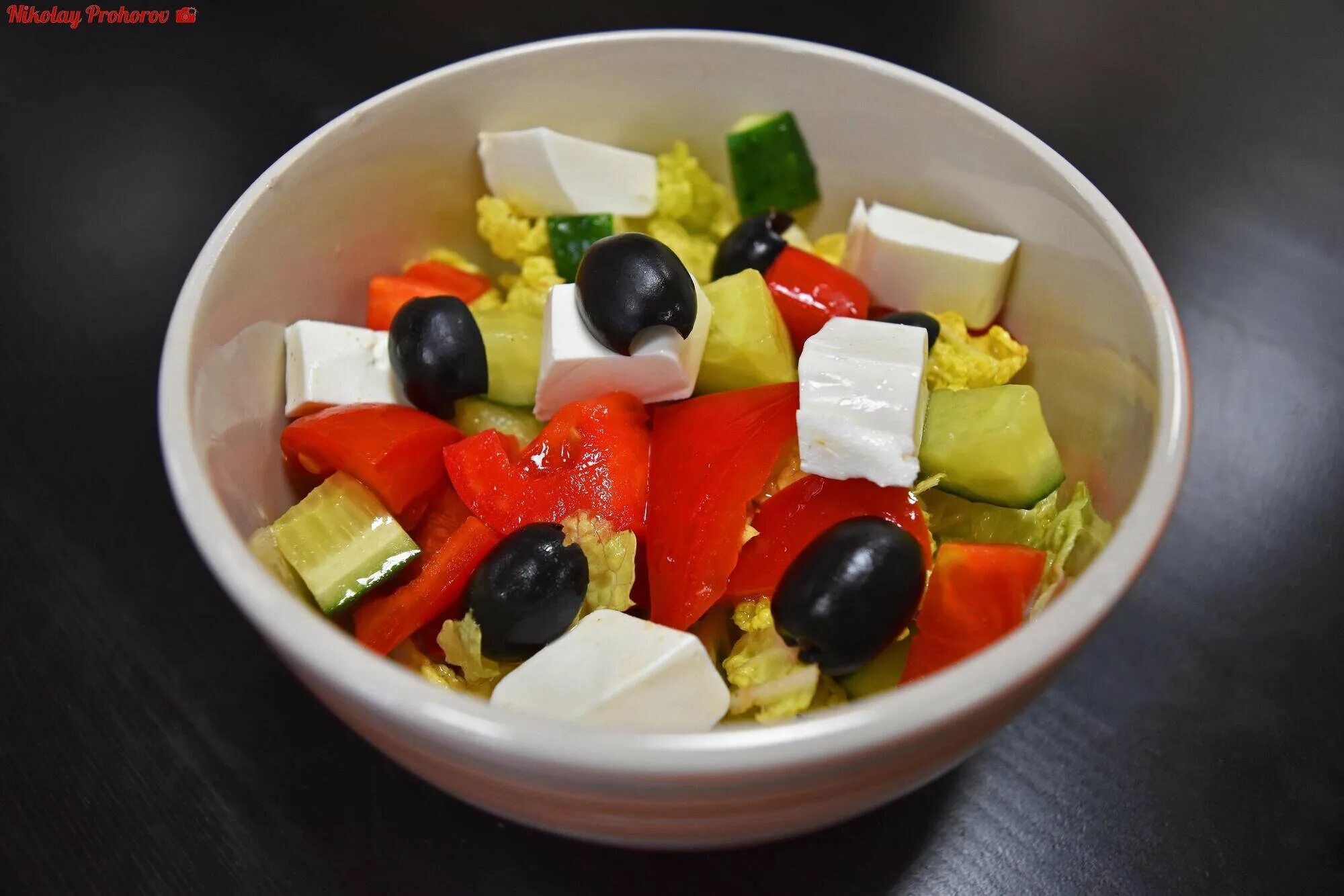 салат греческий 255гр. оригинальный греческий салат. салат греческий на черном фоне. фетакса помидоры,огурцы перец маслины. посуда для греческого салата.