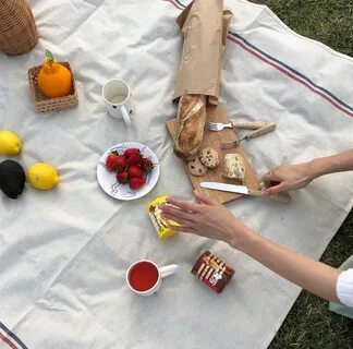 a person sitting on a blanket with food and drinks 