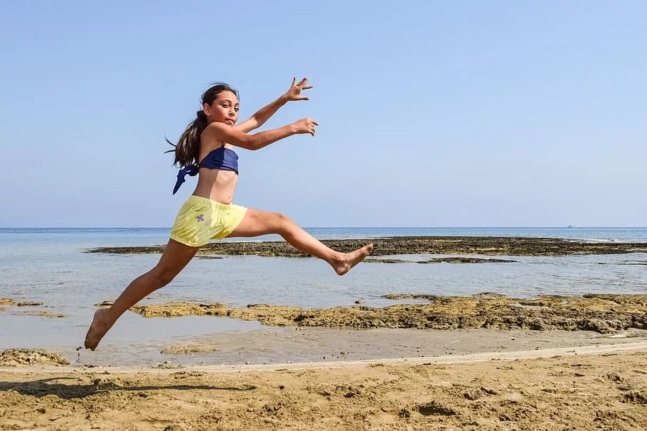Женщина прыгает. Женщина в прыжке. Девушка на пляже с поднятыми руками. Прыжок в море девушка.
