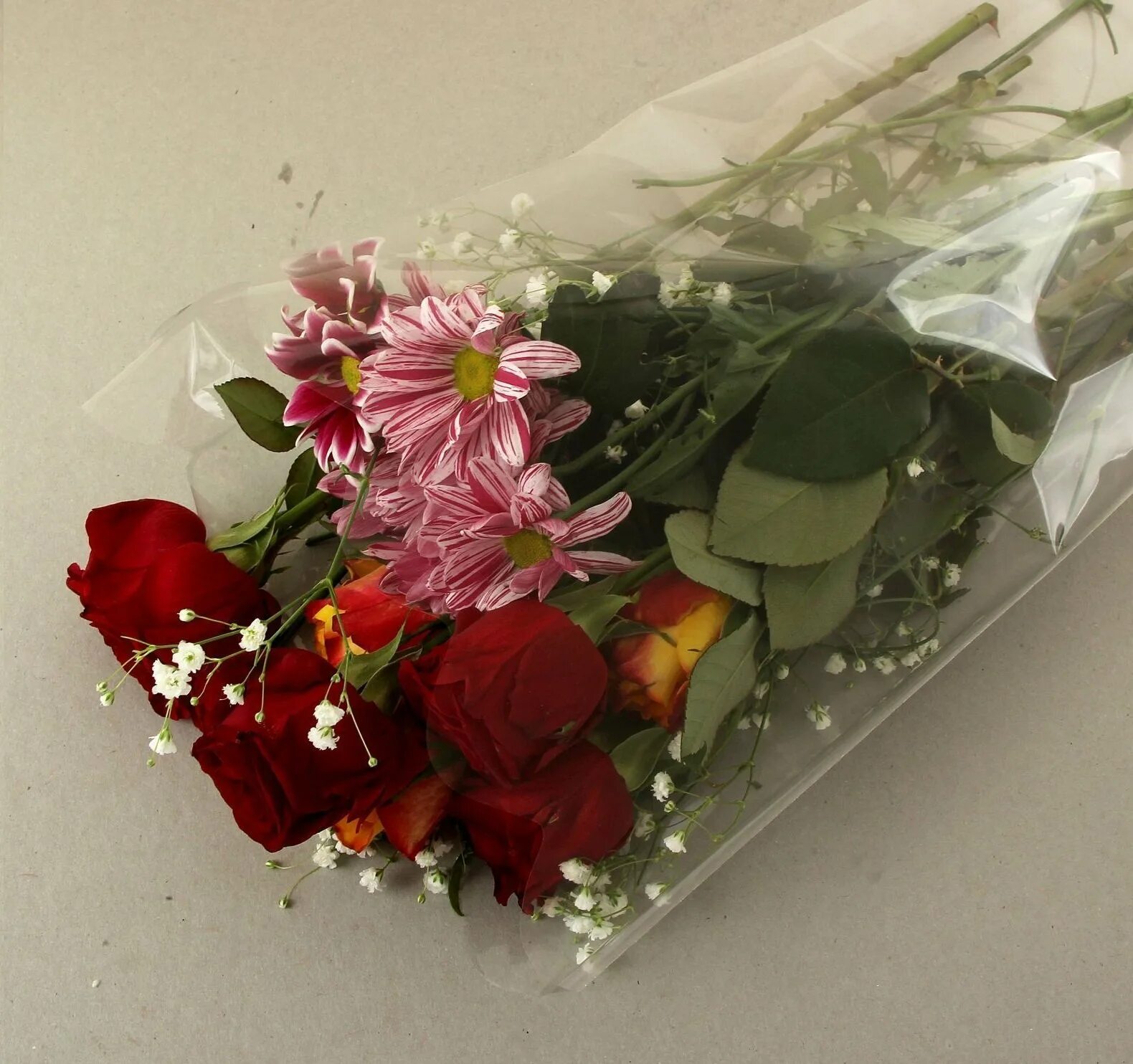 Розы в упаковке как сохранить. Букет цветов в целлофане. Прозрачная упаковка для цветов. Букет роз в целлофане. Букет в прозрачной пленке.