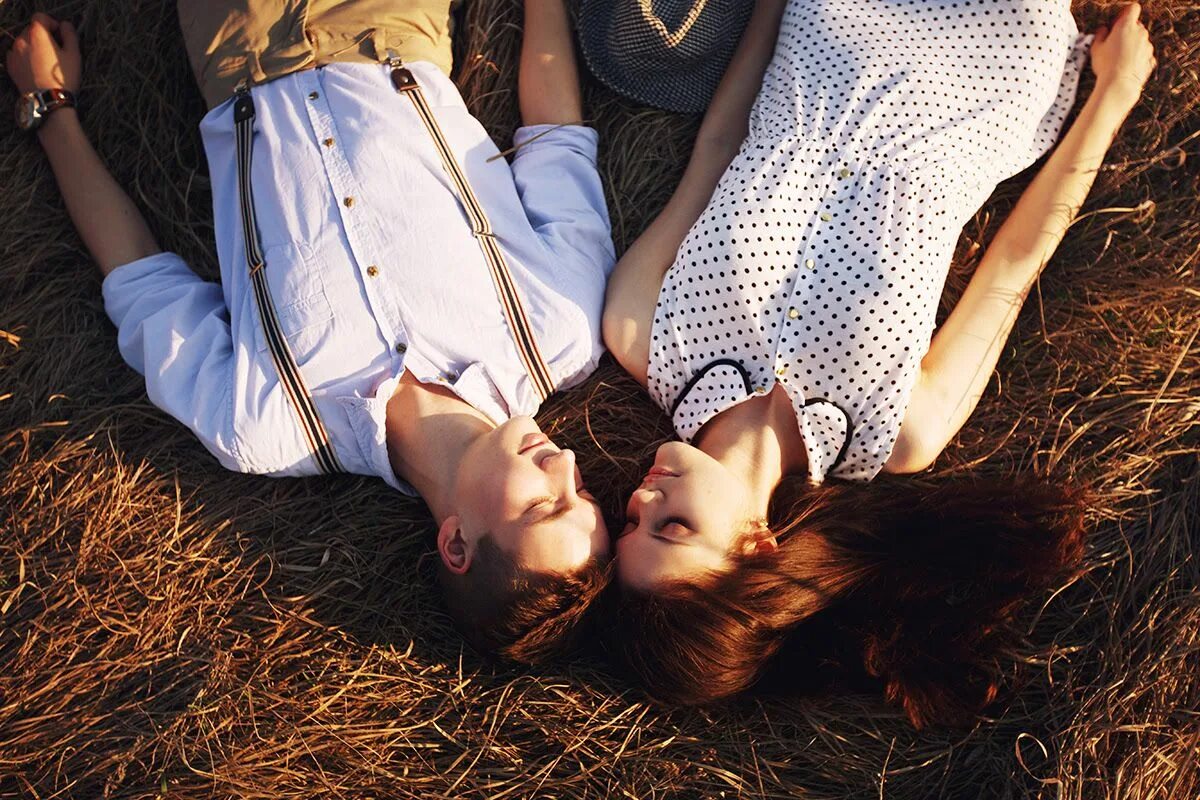 2 молодые девушки и парень. Фотосессия двух девушек. Двое лежат на траве. Две девушки обнимаются. Пара лежит на траве.