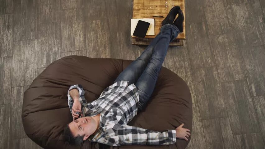 Лежит в кресле. Фото людей лежа. Охранник лежит на диване. Мужчина лежит на диване вид сверху. Лежа сидеть в телефоне