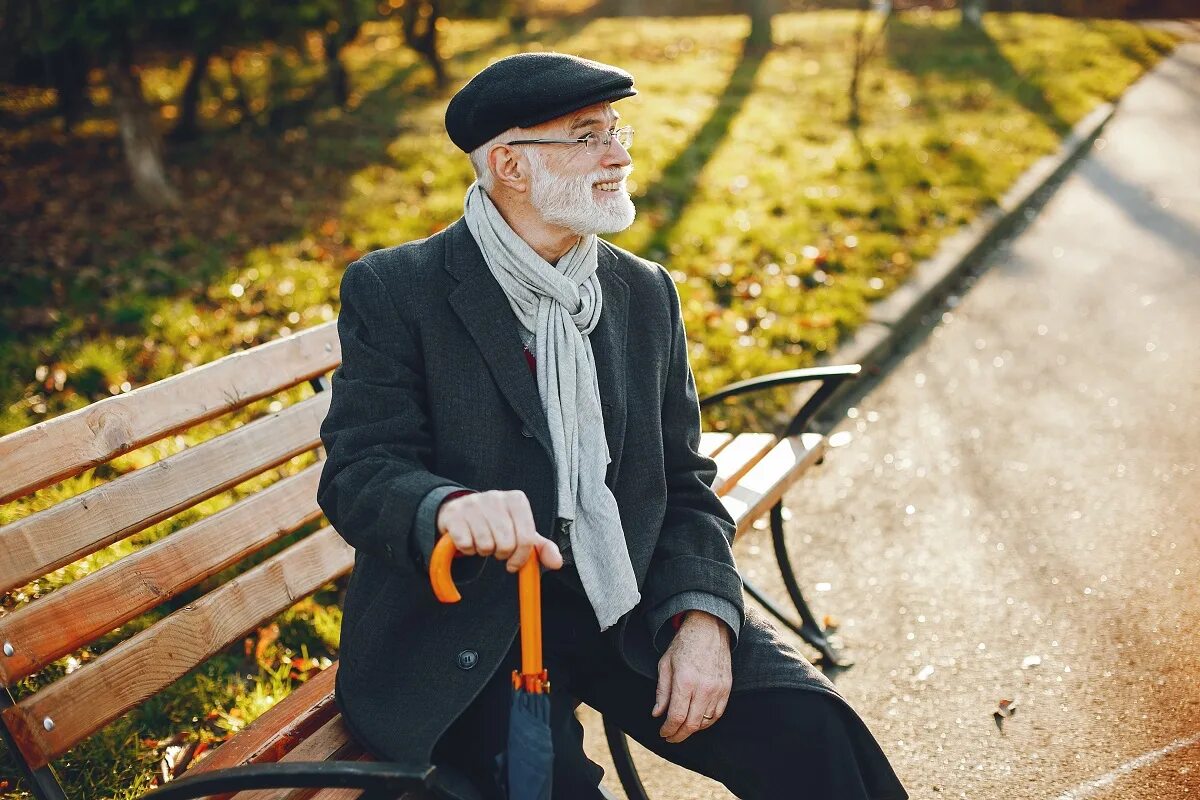 Дедушка с палочкой. Пожилой мужчина в шляпе. Старик на скамейке в осеннем парке. Дедушка в парке.