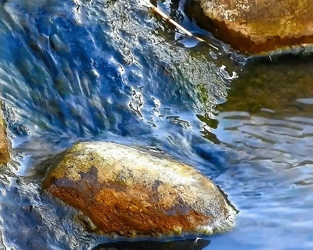 Текущая вода. Красивый камень в ручейке. Валун в воде. Камни в воде. Вода едва блестела в реке