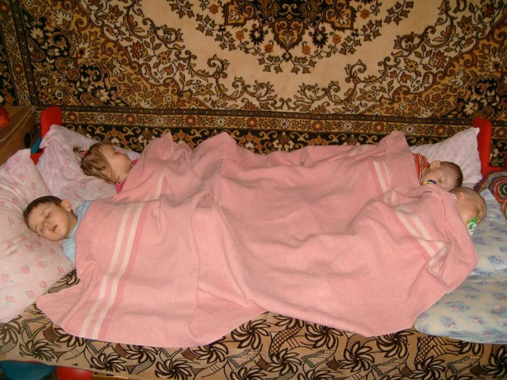 Укрывает ребенка одеялом.