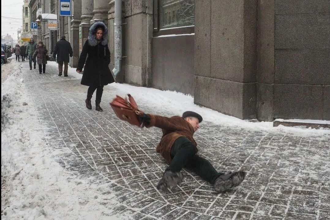 Чуть свалиться. Скользко на улице. Голодед падает человек. Человек падает на льду.