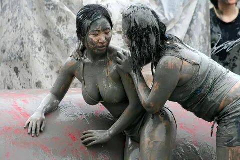 two women are covered in mud while standing next to each other.
