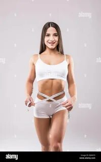 Fitness young woman taking body measurements isolated over a white backgrou...