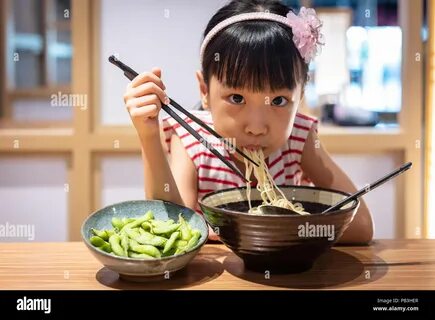 Asian little Chinese girl eating ramen noodles at a Japanese restaurant Sto...