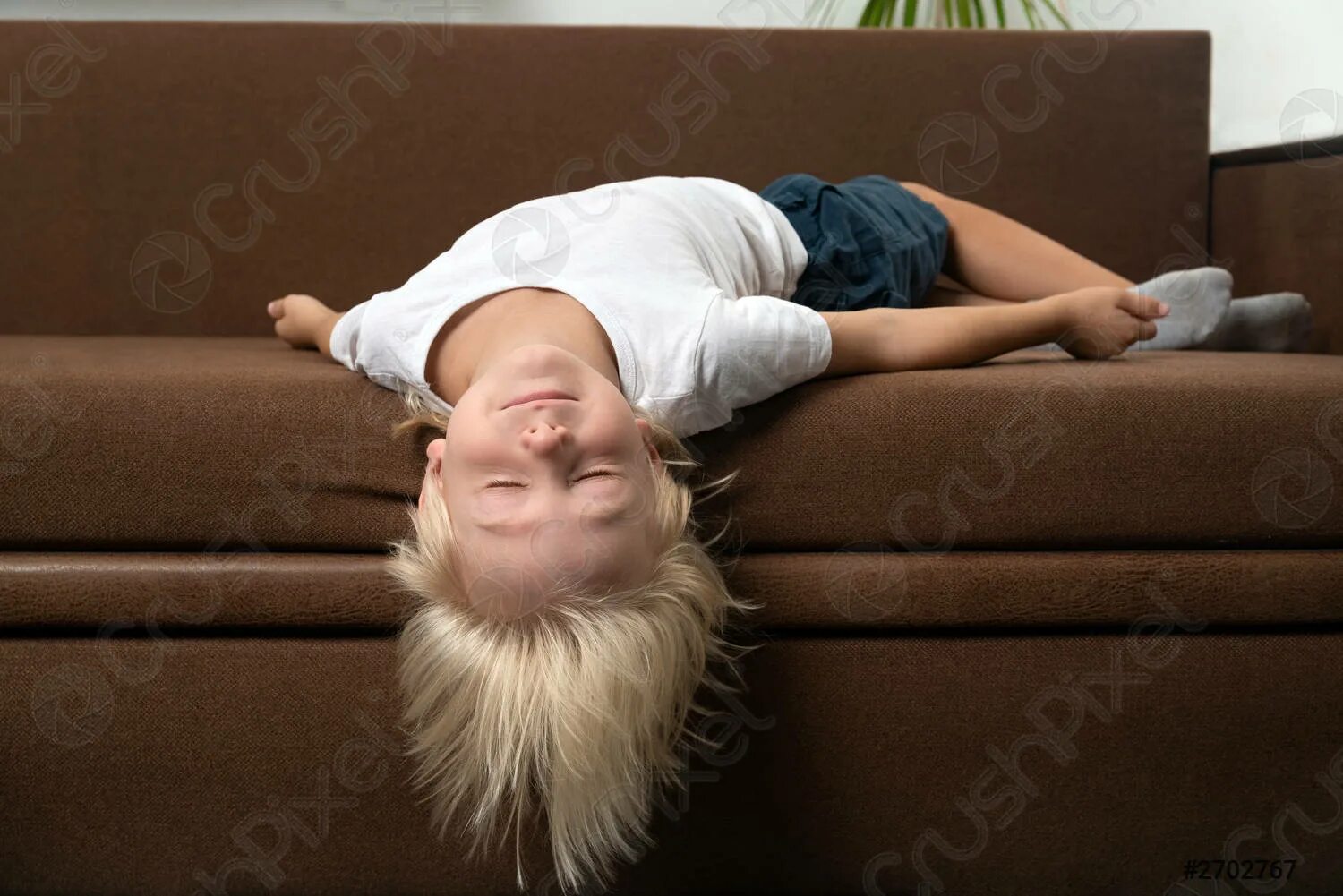 Мальчик устала. Уставший ребенок. Голова свисает с кровати. Ребенок лежит на диване.