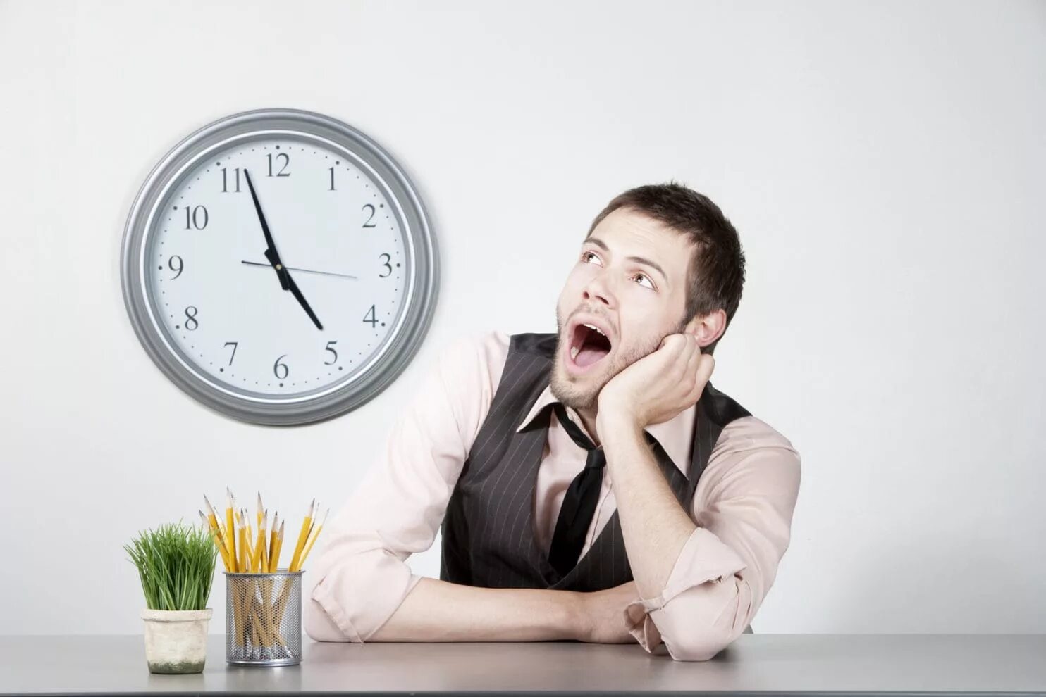 Среди рабочего дня. Смотрит на часы на работе. портрет рабочего дня. человек с часами на работе. в ожидании конца рабочего дня.