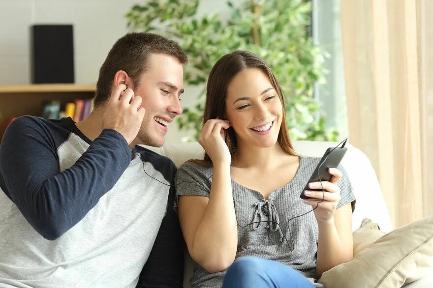 A couple at Home looking at the Phone. Happy couple looking through Window. Парочка слушает музыку. Домашнее с разговором в контакте