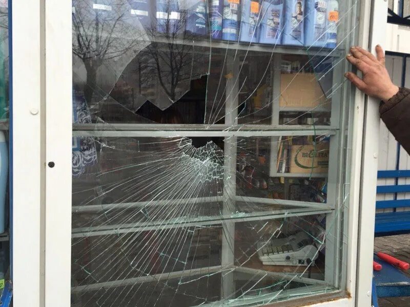 человек разбивает окно. разбить окна в магазине. сломанная форточка. разбитый стеклопакет. разбил витрину в магазине.