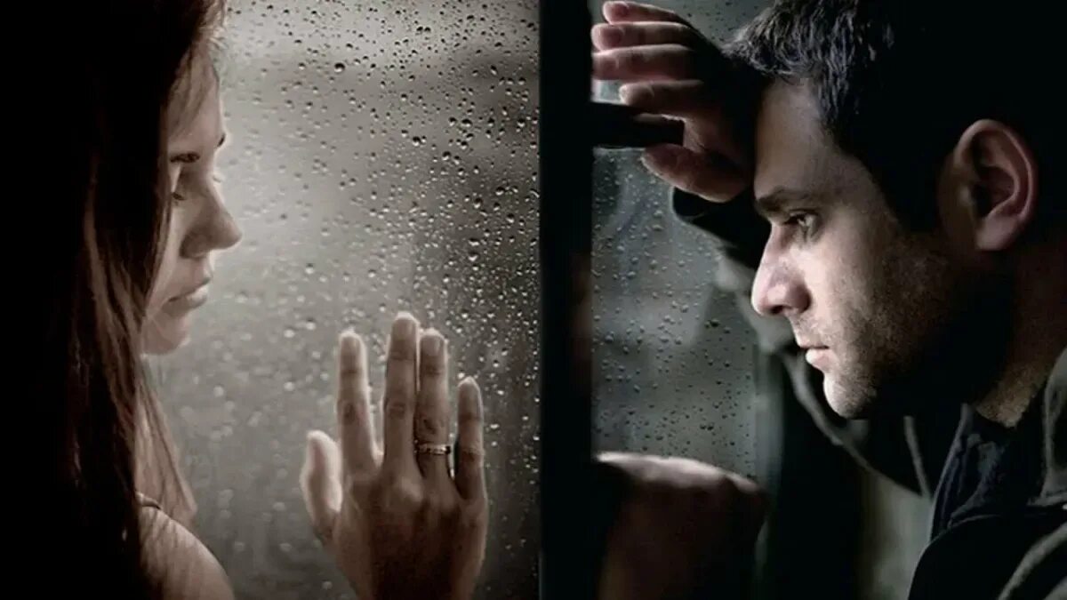 Встречая и расставаясь. Мужчина и женщина через стекло. Мужчина и женщина грустные. Два разных человека.