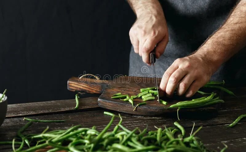 Cutting green. Дорогая разделочная доска из темного дерева. The man is Cutting the Board.