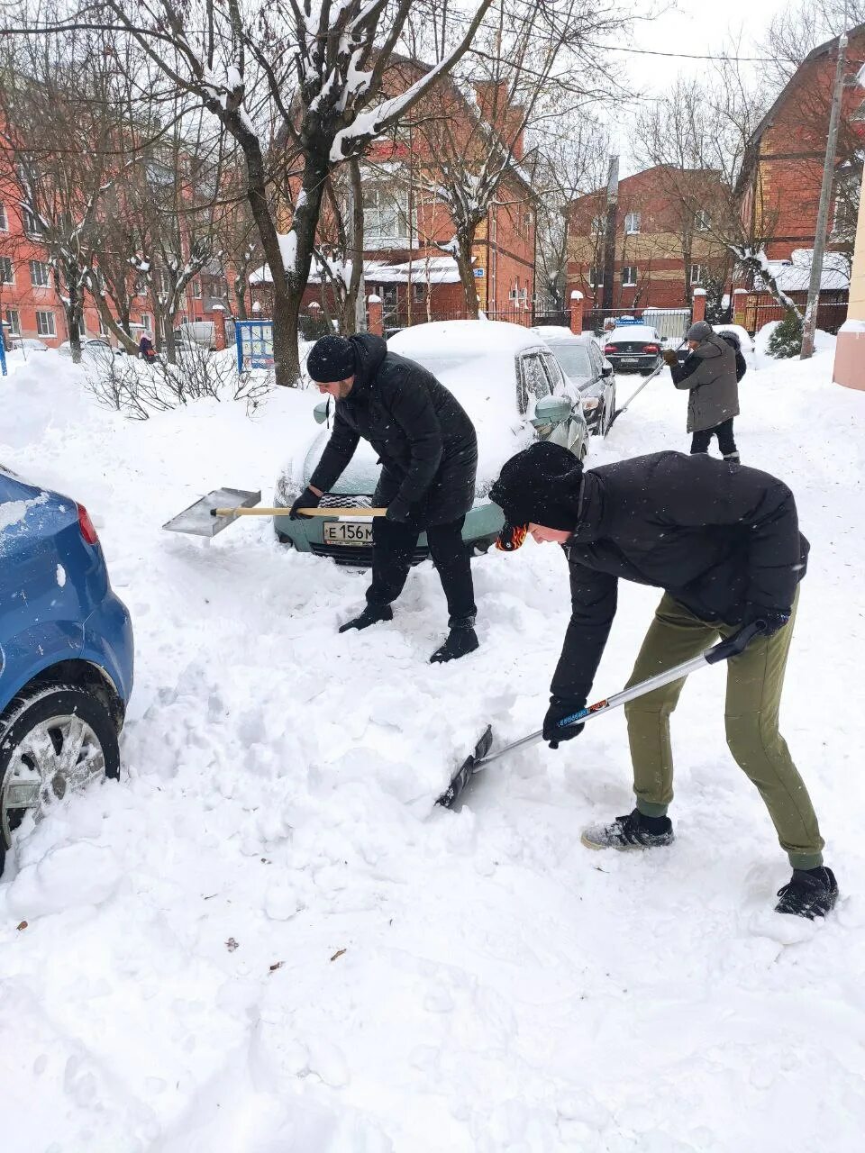 Убирает снег. Сугробы во дворе. Убирают снег во дворе. Много снега во дворе.