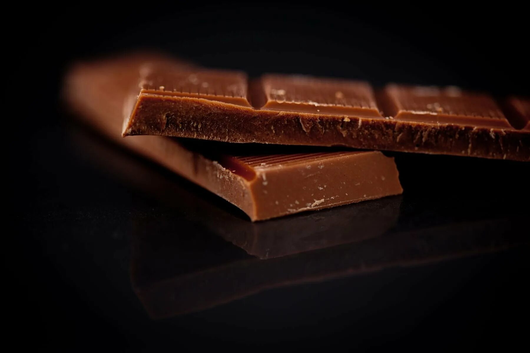 Темный шоколад фото. Шоколад на черном фоне. Плитка шоколада на черном фоне. Молочный шоколад на темном фоне. Кусочек шоколад на черном фоне.