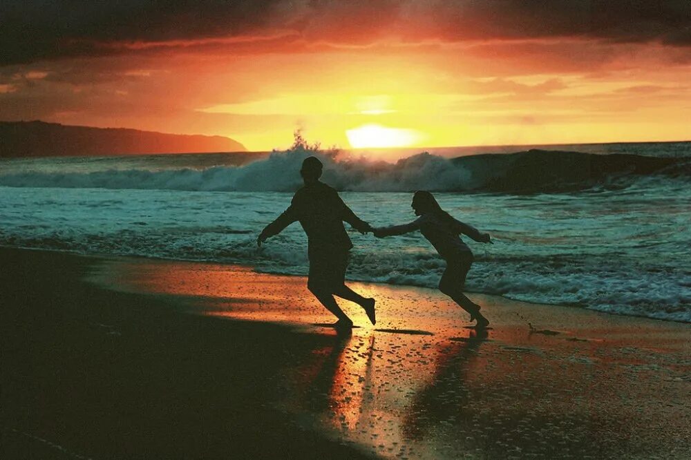 Мчась навстречу жизни и любви. Пара бежит по берегу моря. Двое бегут. Двое бегут по берегу. Пара убегает в закат.