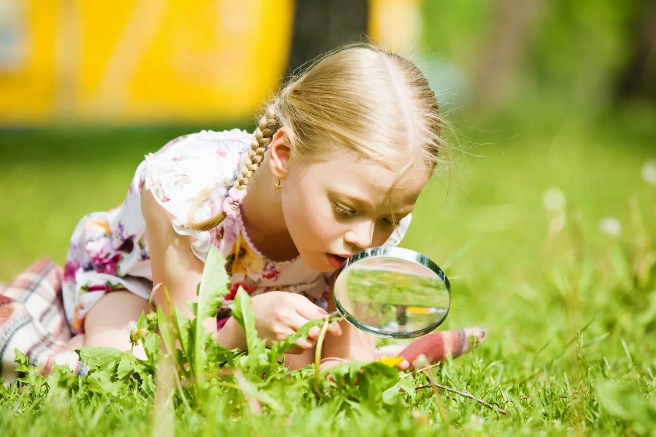 Мир любопытство. Дети и природа. Девочка с лупой в траве. Любознательный ребенок. Изучение природы.