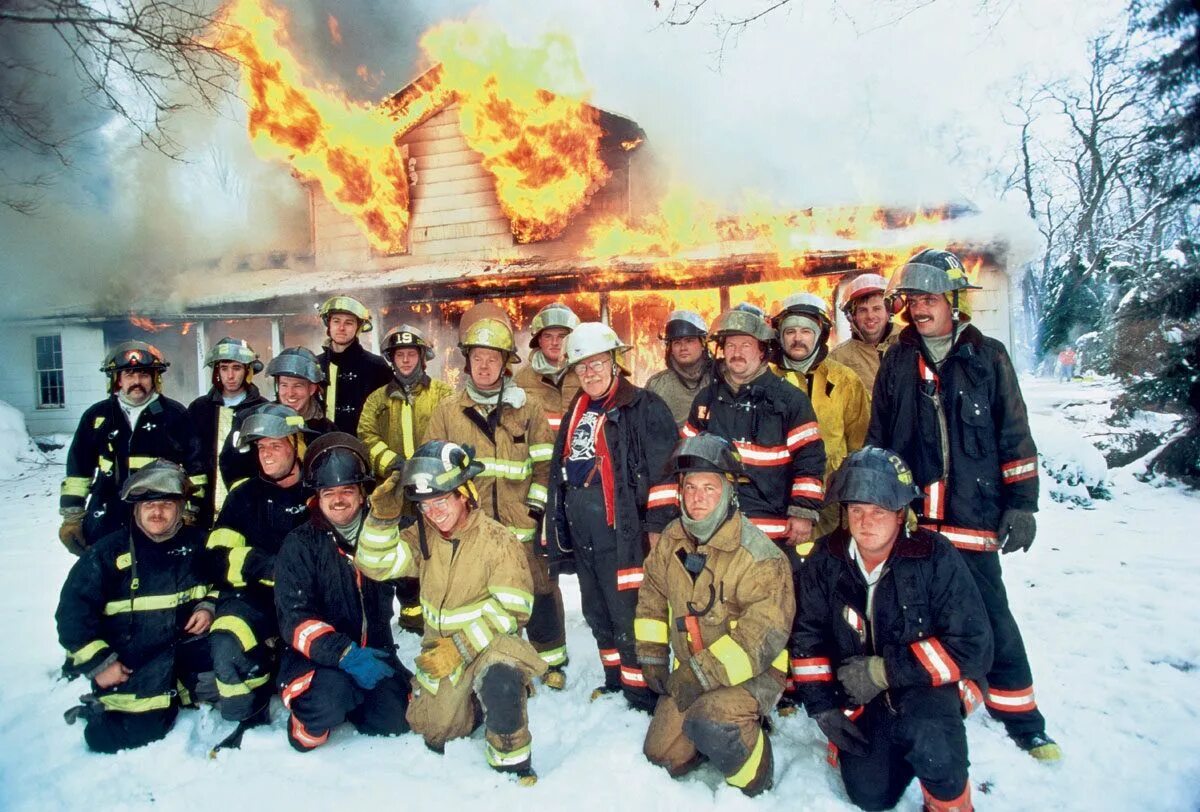 Спасательный дом. Пожарный на фоне пожара. Пожарные на фоне горящего дома. Фото пожарных. Пожарник на фоне пожара.