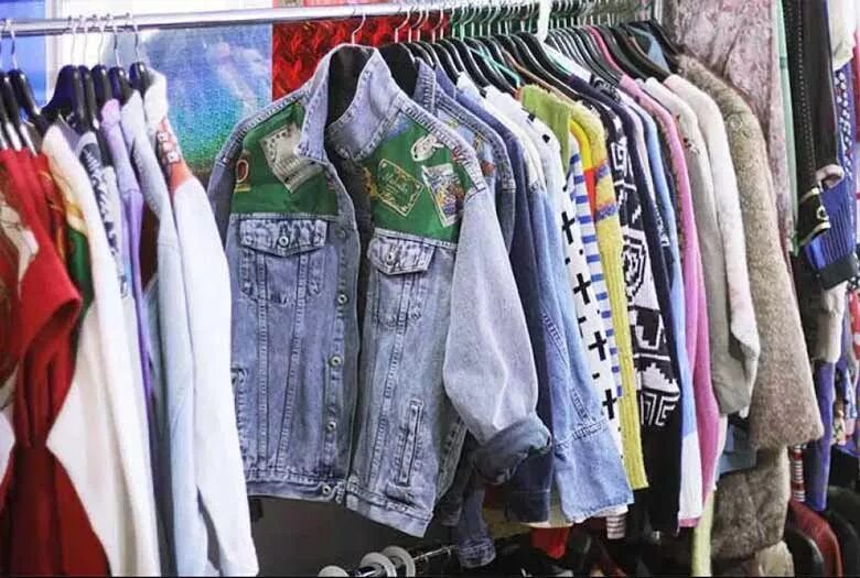 Вещи для женщин. Фон для торговли одеждой. Стоковые вещи. Недорогие вещи. Девушка выбирает одежду в магазине.