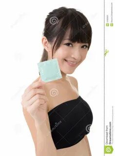 фото около Женщина детенышей довольно азиатская с презервативом в ее руке. 