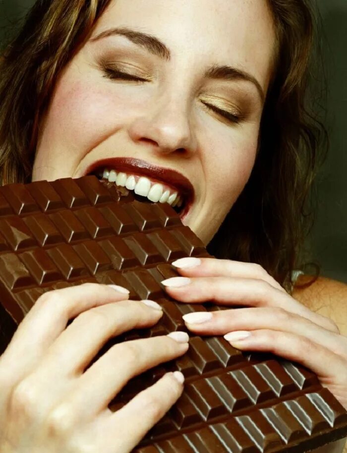 Шоколад и здоровье. Девушка ест конфету. Девушка с шоколадкой. Поедание шоколада. Наслаждение от шоколада.