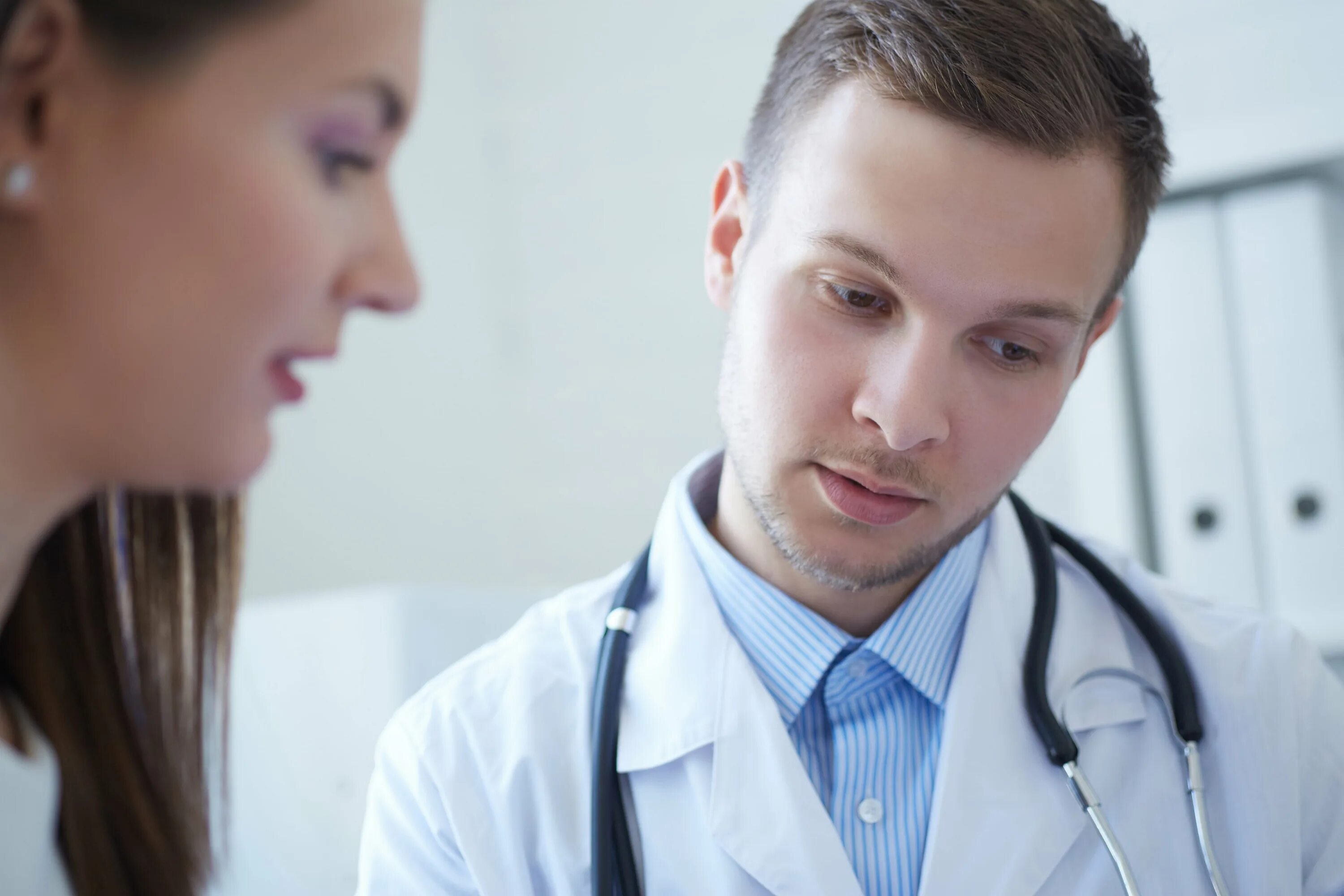 Врач молодой разговаривает по телефону. Нетипичный пациент на белом фоне. Hospital staff. Юноши и девушки, врачи. Девочка беседует с врачом.