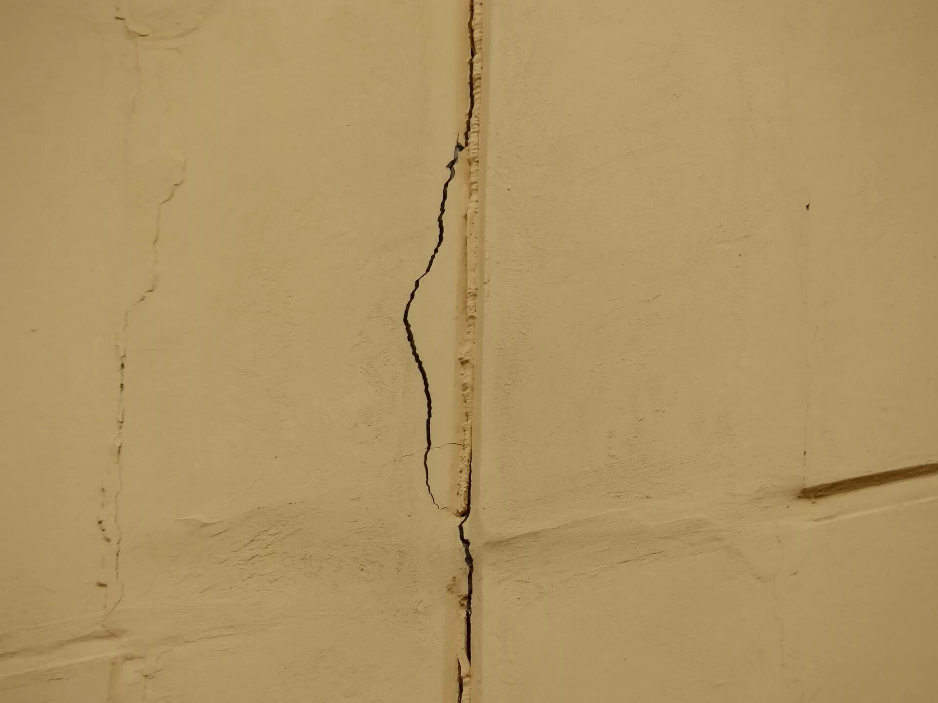На стене появились трещины. Усадочные трещины в штукатурном слое. Трещина на штукатурке на стене. Трещины в перегородках. Сквозная трещина в стене.