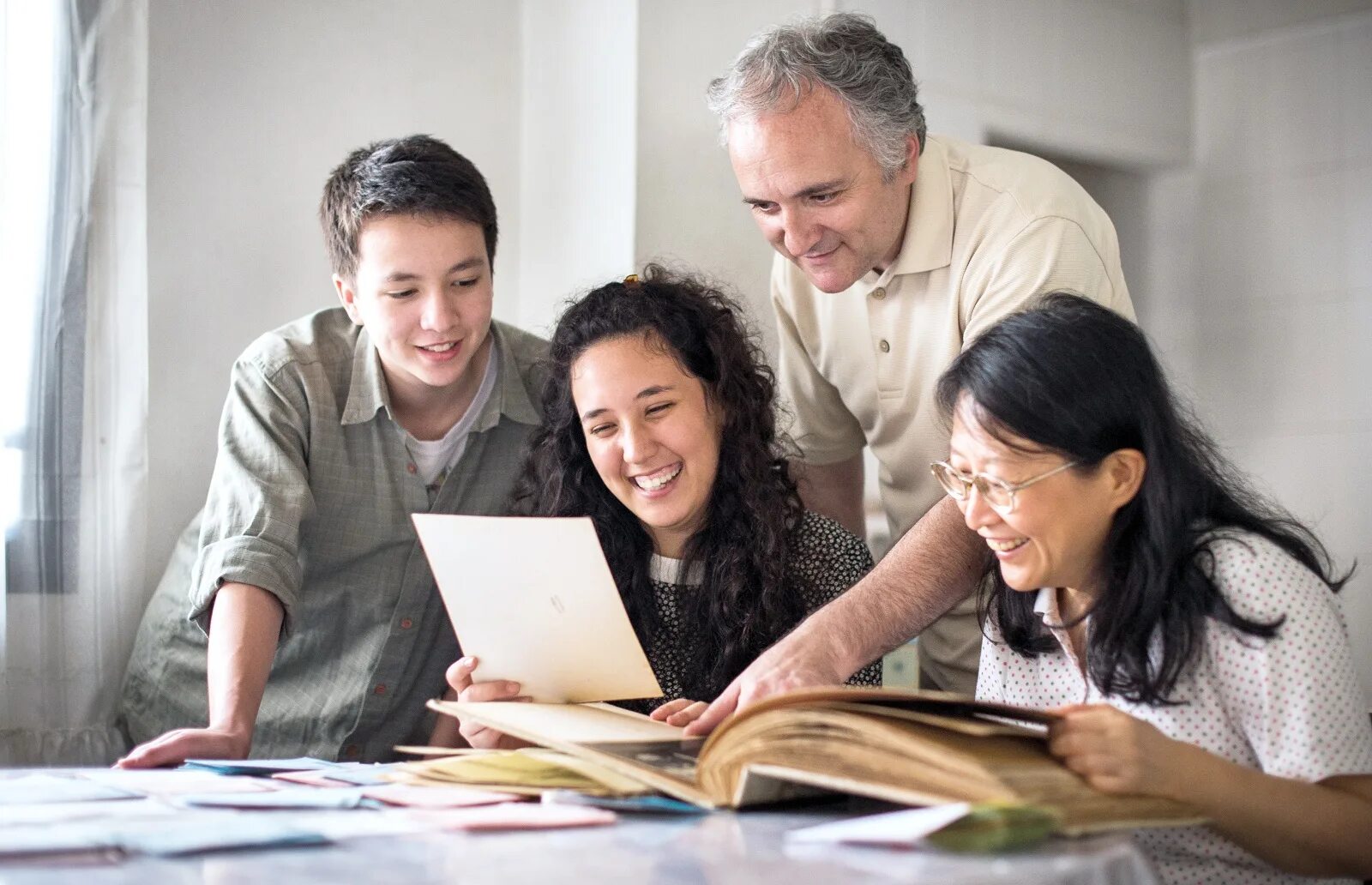 Family History. Продвинутые родители. Семья рассматривает фотоальбом. Рассматривать семейный альбом. Семейная история читать