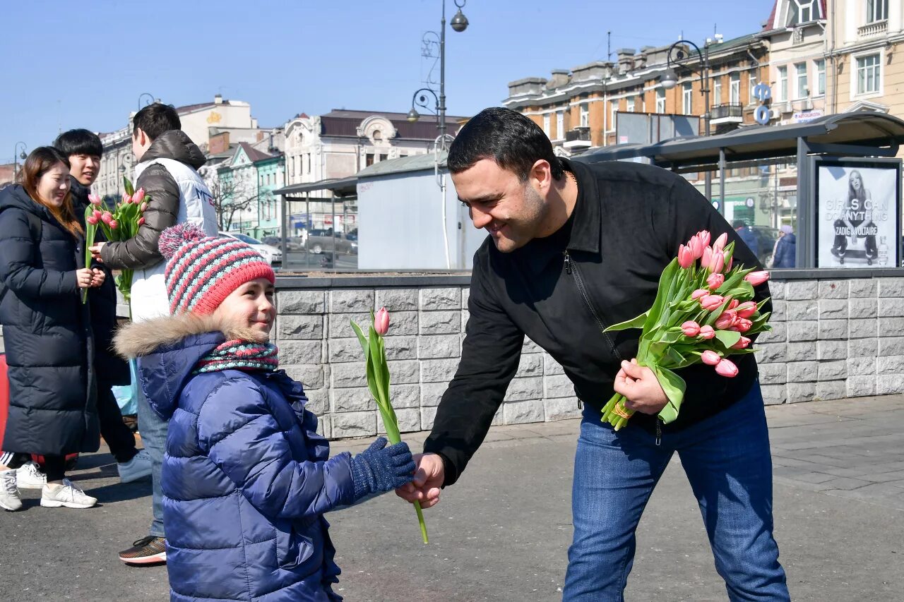 Мужчина с цветами на улице. Праздник на улице с цветами.