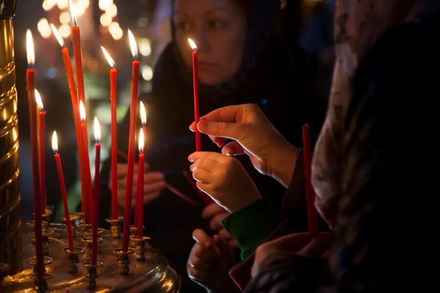 Почему в церкви ставят свечи. Свечи в храме. Красная свечка в храме. Красные свечи в храме. Девушка ставит свечу в храме.