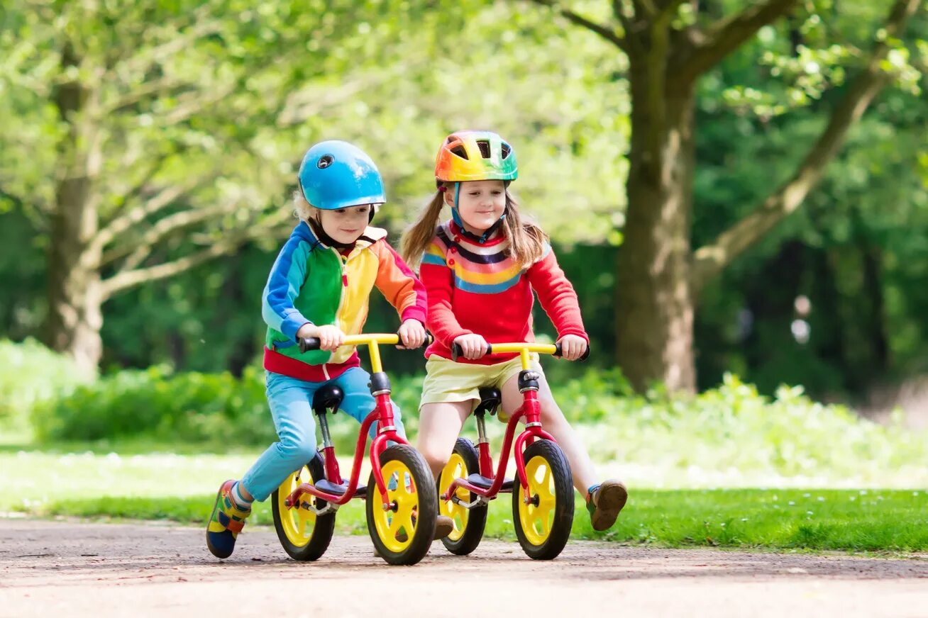 Правильный беговел. Дети с велосипедом. Детский велосипед в парке. Катание на велосипеде в парке дети. Дети в экипировке в парке.