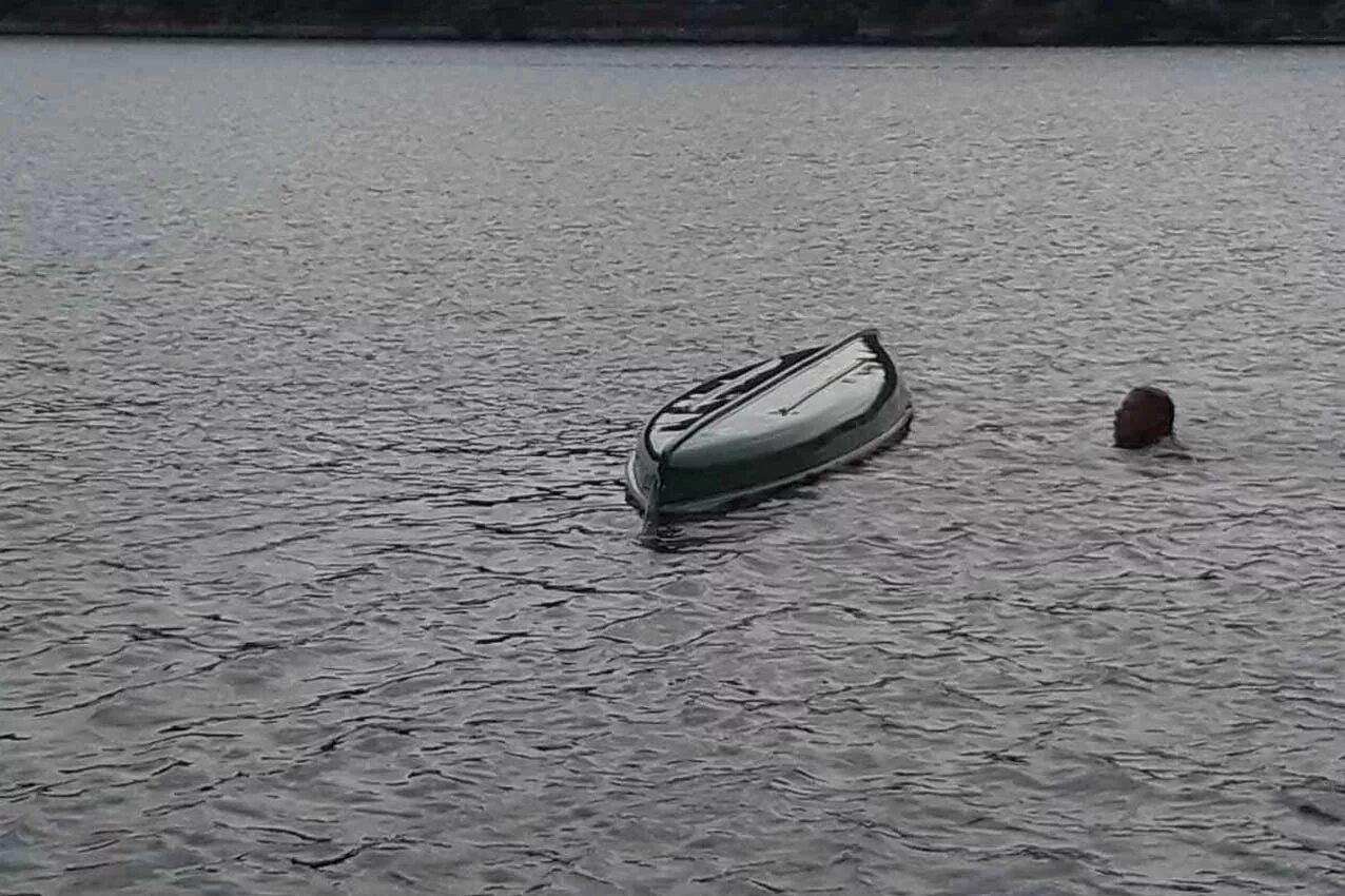 лодка на воде. опрокинутая лодка. старая лодка. катер перевернулся. лодка тонет.