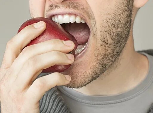 Человек кусает яблоко. Человек ест яблоко. Крепкие зубы.