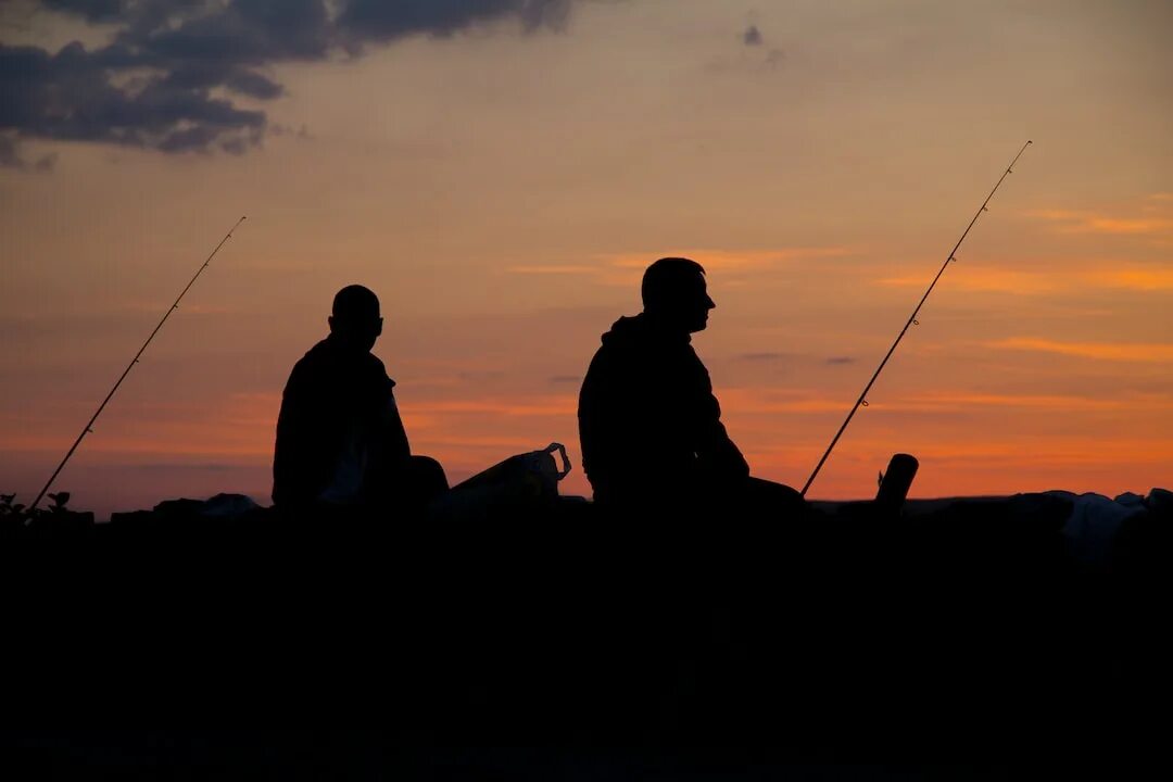 Два рыбака. Мужчина на рыбалке. Два рыбака на берегу. Рыбак на фоне заката.
