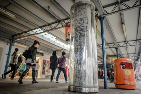 Pedestrians walk past a plastic casing set up around a graffiti made by the...