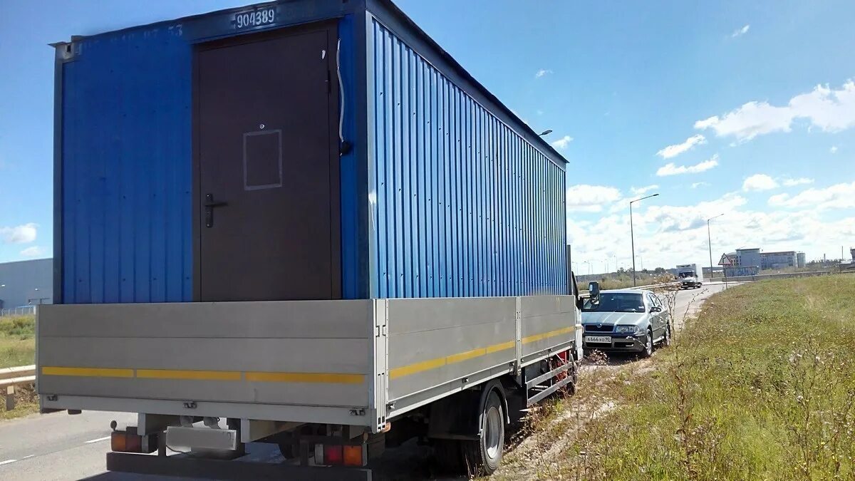 транспортировка бытовки. перевозка строительных бытовок. перевозка строительных бытовок. погрузка бытовки манипулятором. низкорамник для перевозки бытовки.