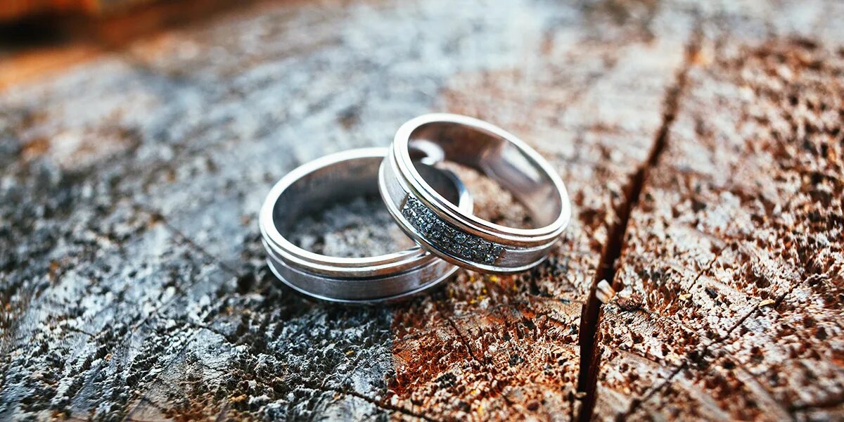 Можно переплавлять обручальные кольца. Свадебные кольца на дереве. Свадебные кольца на столе. Свадебные кольца фото. Обручальные кольца лежат.