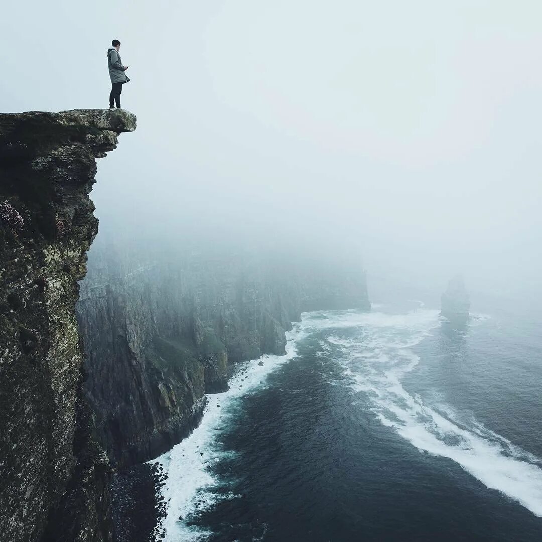 Море скалы. Человек на обрыве. Норвегия скала язык тролля несчастные случаи. Человек над обрывом. Огромные скалы.