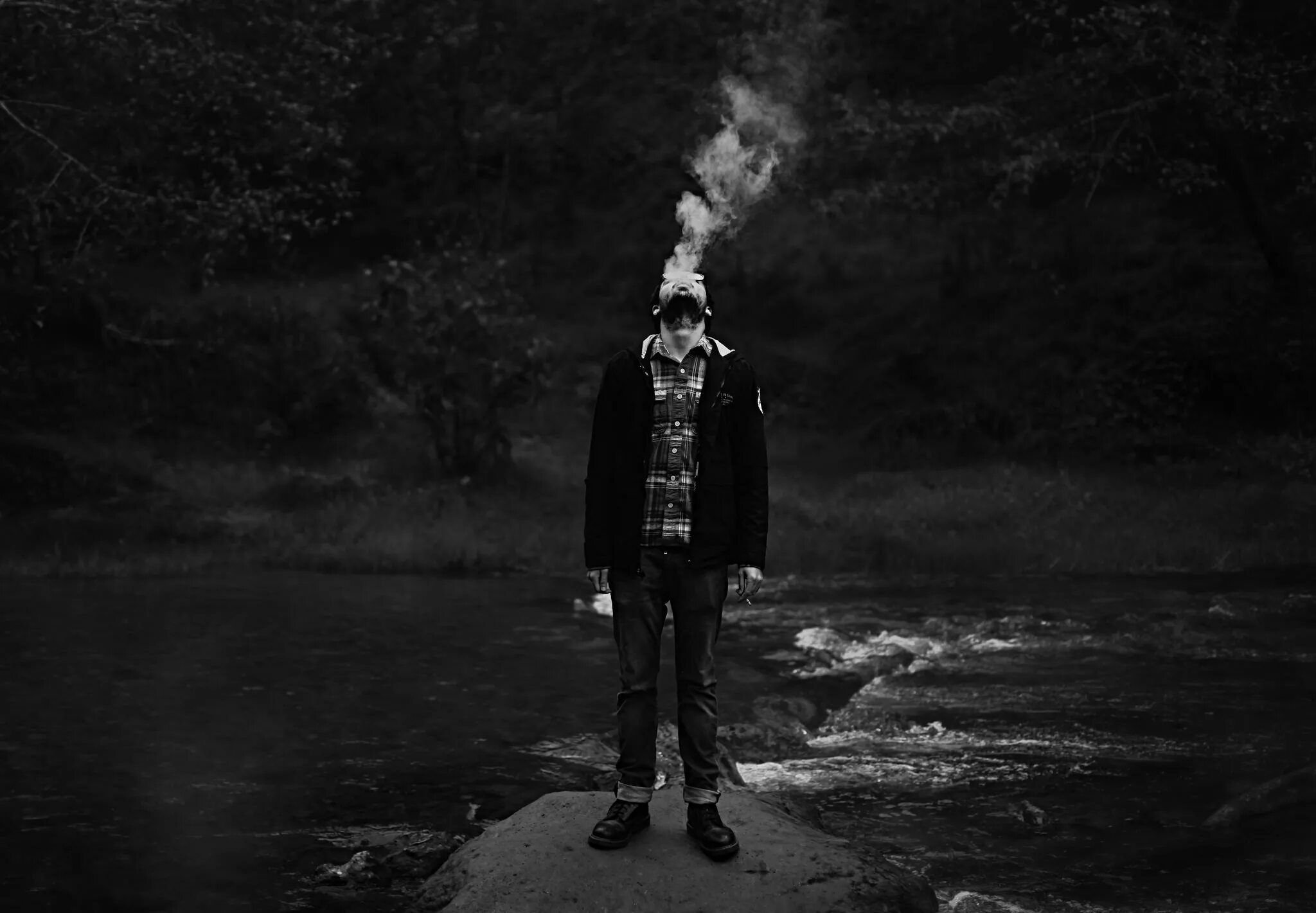 парень курит. выпускает дым. мужчина в дыму. парень с сигаретой. парень с сигаретой в темноте.