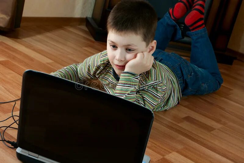 Мальчик играет на полу. Мальчик с ноутбуком. Ребенок лежит и играет в компьютер. Фото мальчика который играет в комп.