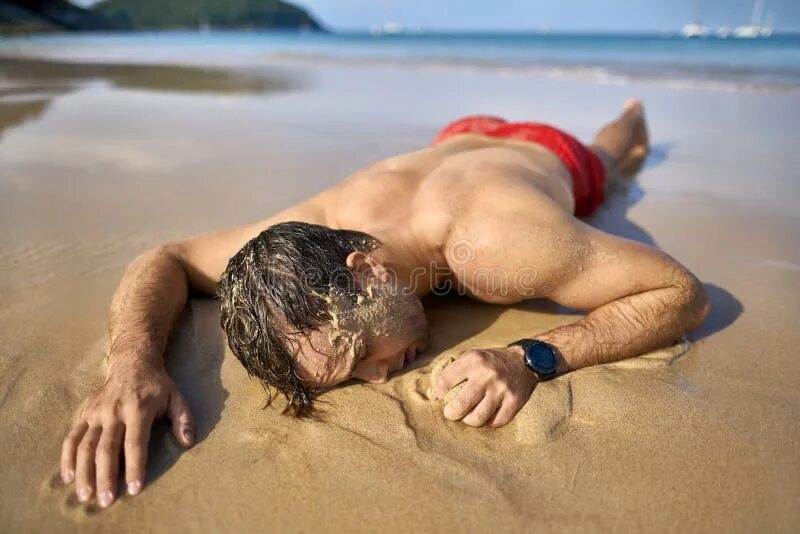 Пока спал на пляже. Мужчина лежит на пляже. Парень лежит на пляже. Парень лежит на песке. Мужчина загорает на пляже.