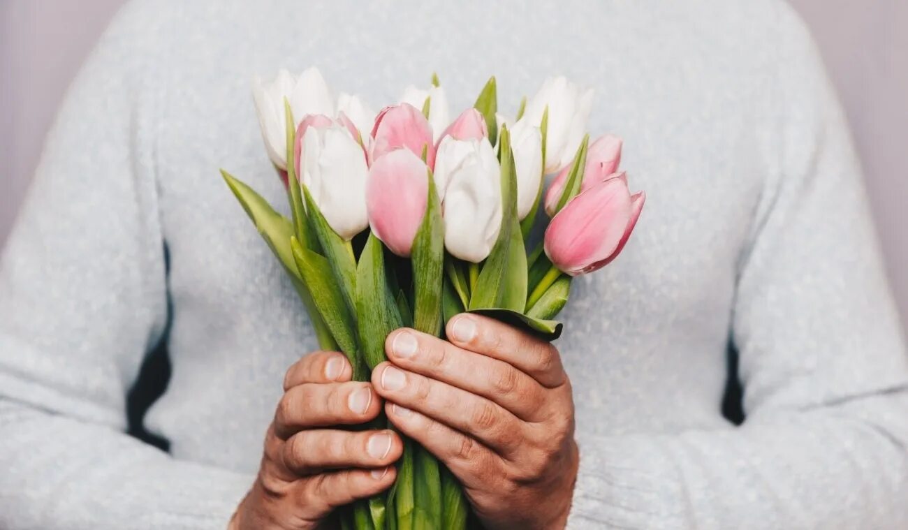 Можно дарить 1 тюльпан. Цветы в руках мужчины. Букет цветов в руках. Букет тюльпанов в руках. Мужчина с тюльпанами.