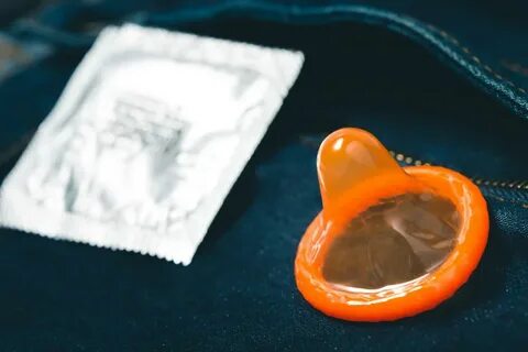 Condom and wrapper on denim jeans. 