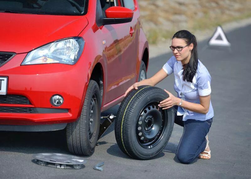 Колесо автомобиля. Женщина меняет колесо. Замена колеса на автомобиле. Девушки меняют колесо на машине.