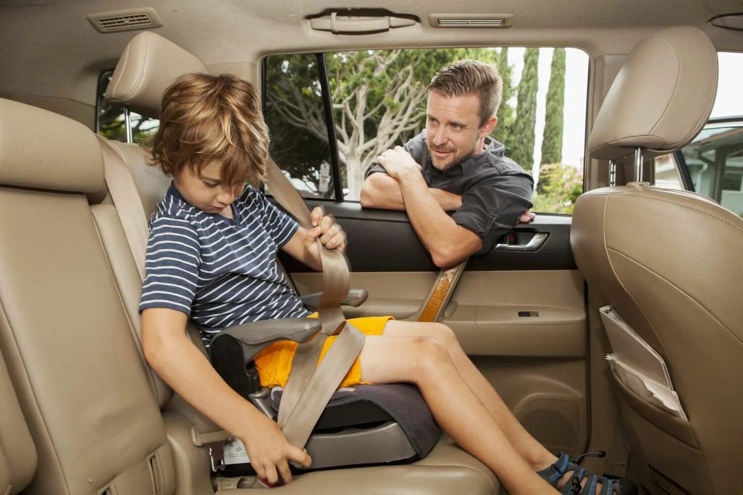 Бустер для детей. Children in the back Seat of the car. Пристегнутый пассажир. Салон автомобиля изнутри с детским креслом.